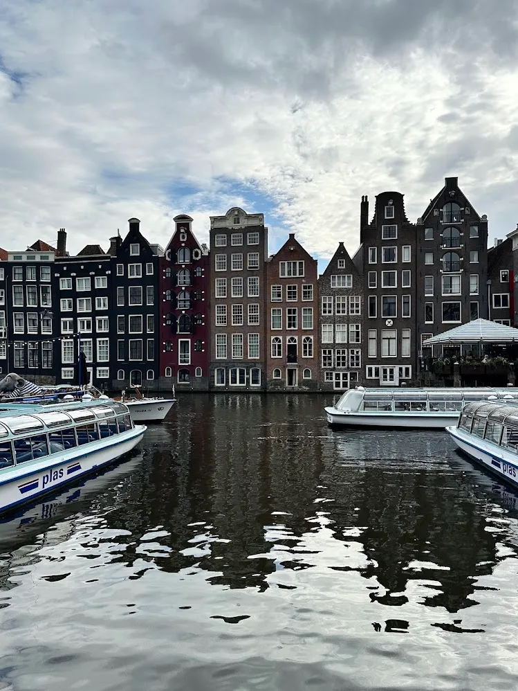 Casas de canal y barcos turísticos con techo de vidrio en un canal de Ámsterdam