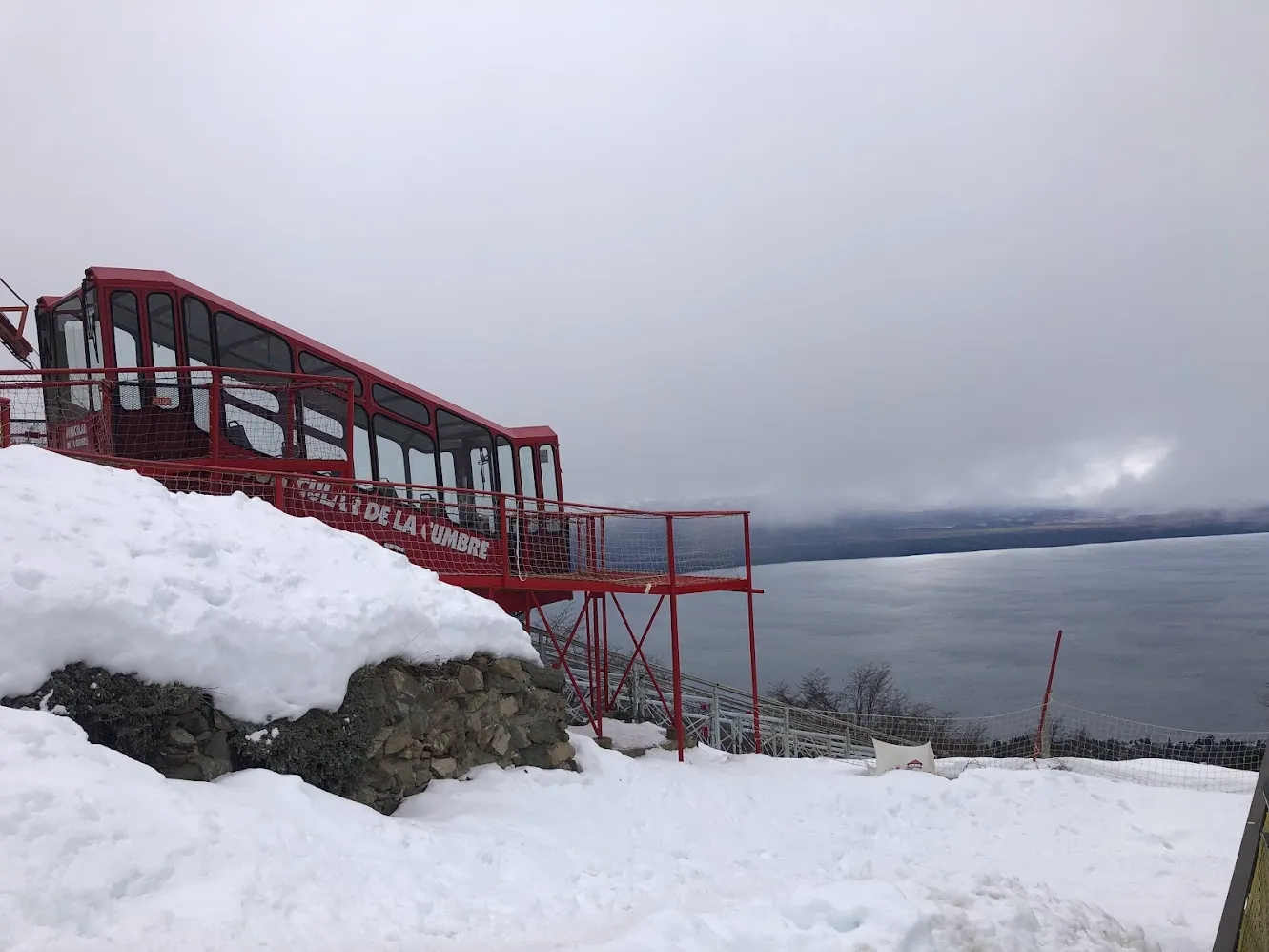 Un funicular rojo subiendo una ladera nevada sobre el lago Nahuel Huapi en Bariloche