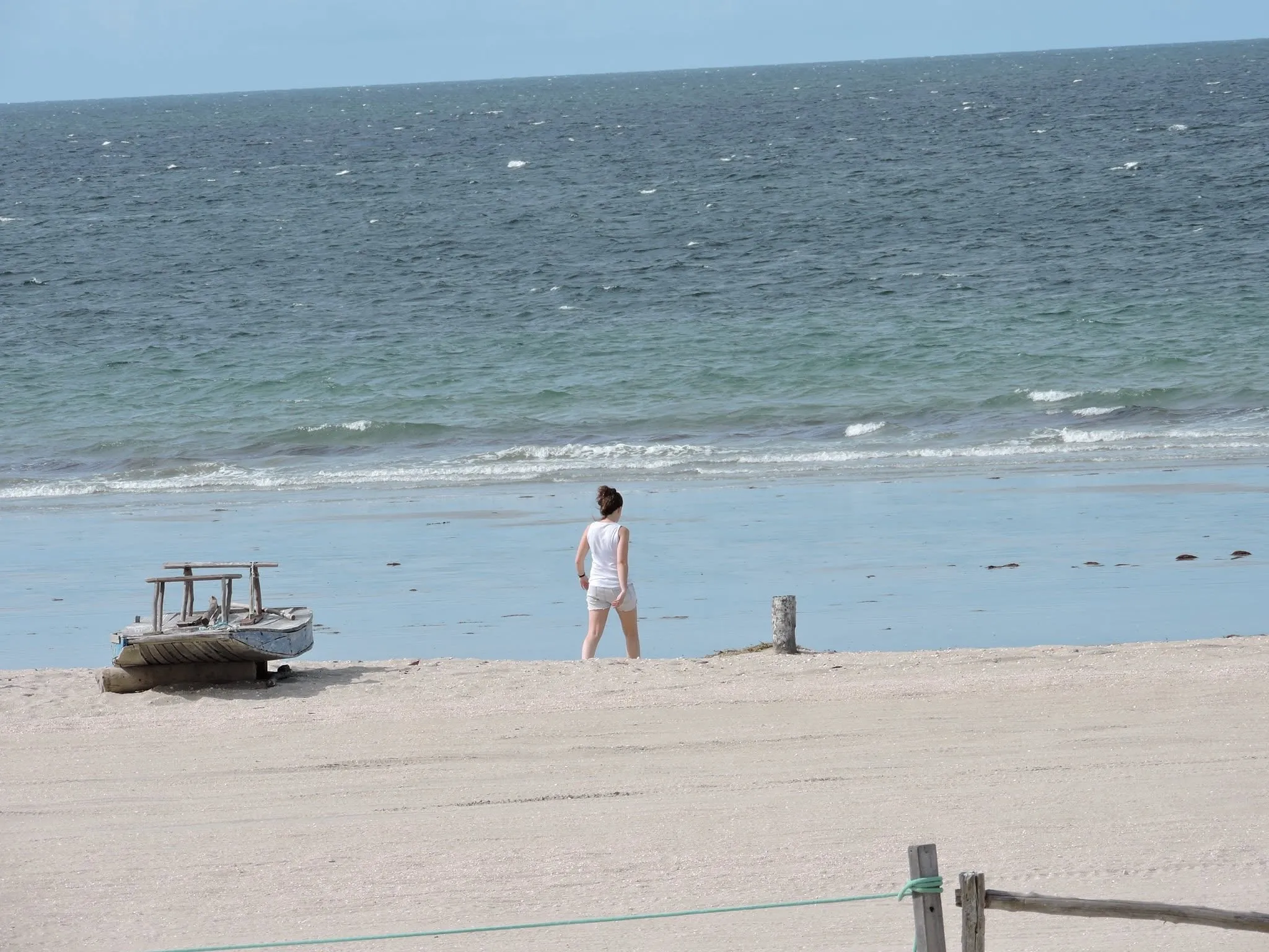 Caminando hacia el mar junto a un bote de madera en una playa brasileña soleada