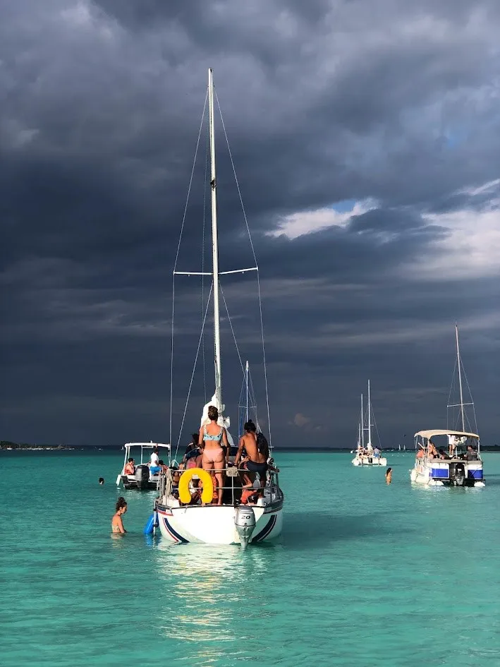 Un velero en aguas turquesa del Caribe bajo un cielo tormentoso