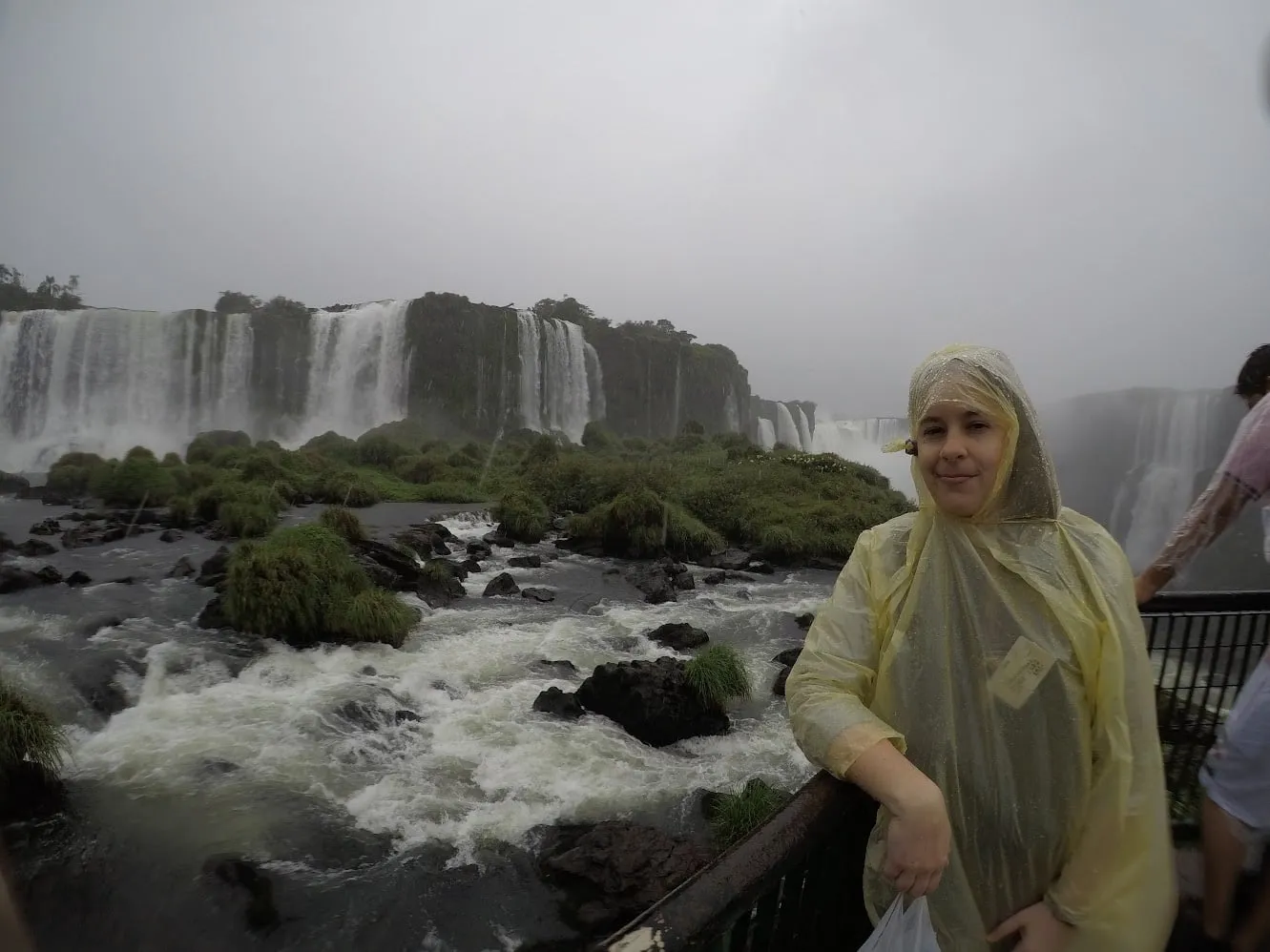 Con poncho amarillo en las Cataratas del Iguazú entre niebla y cielo gris