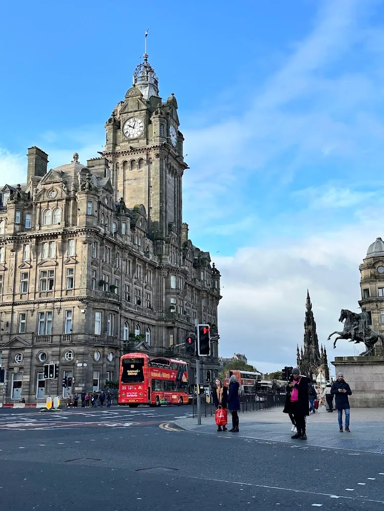 Un bus turístico rojo pasando frente al Hotel Balmoral y el monumento a Scott
