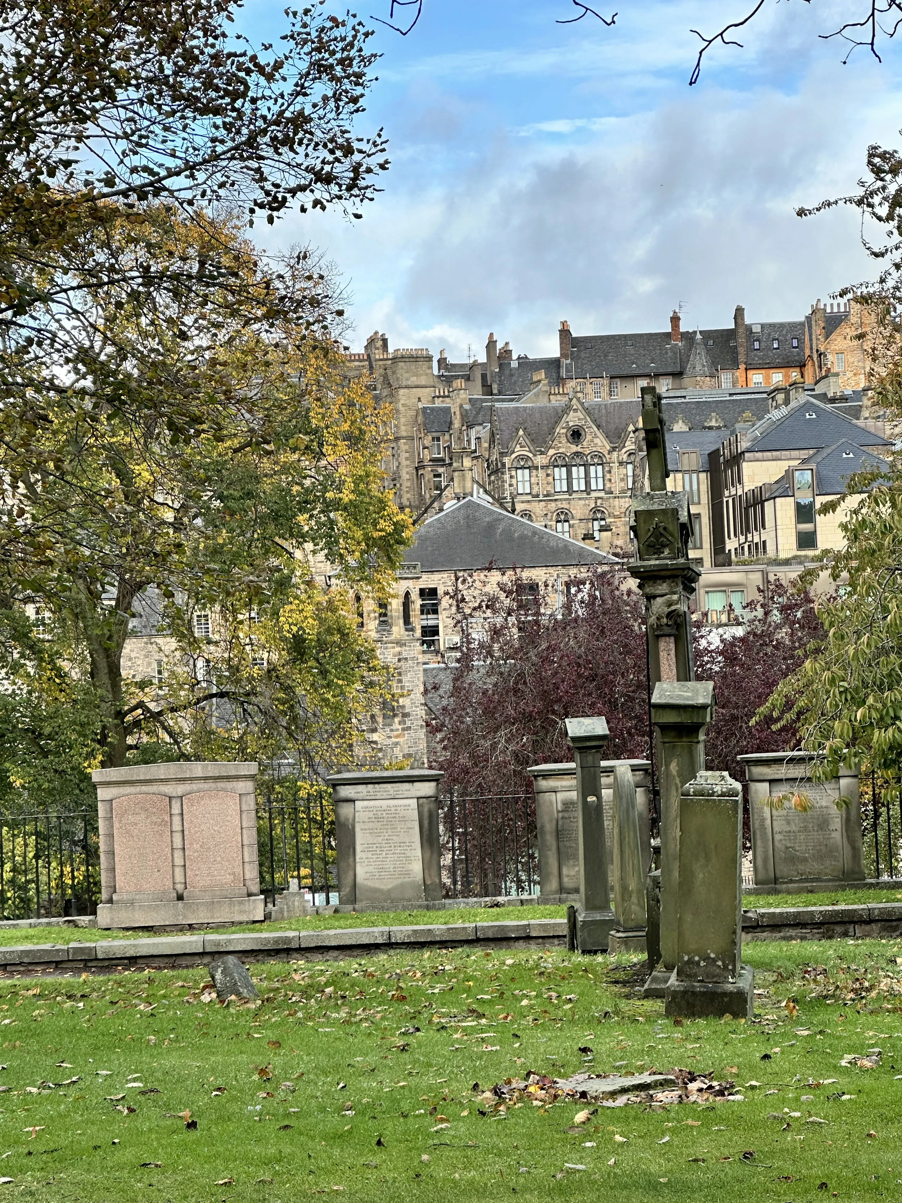 Lápidas históricas en un cementerio con la Ciudad Vieja de Edimburgo al fondo