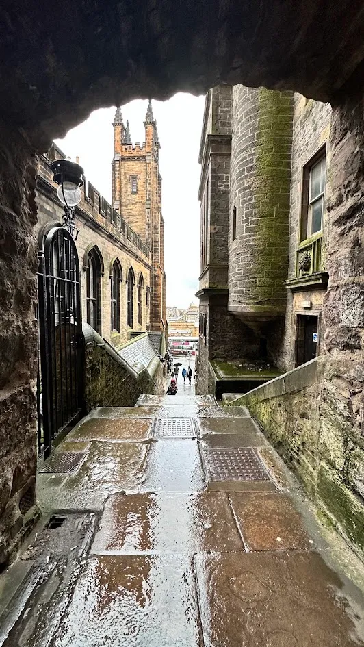 Un pasaje de piedra mojado en la Ciudad Vieja de Edimburgo enmarcado por un arco oscuro