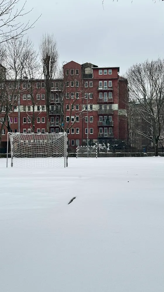 Una cancha de fútbol cubierta de nieve con arcos frente a un edificio de ladrillo