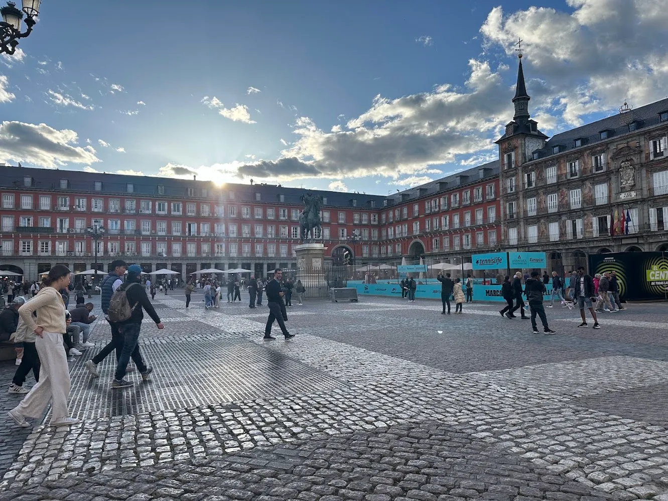Personas cruzando la Plaza Mayor de Madrid bajo el cielo de la tarde