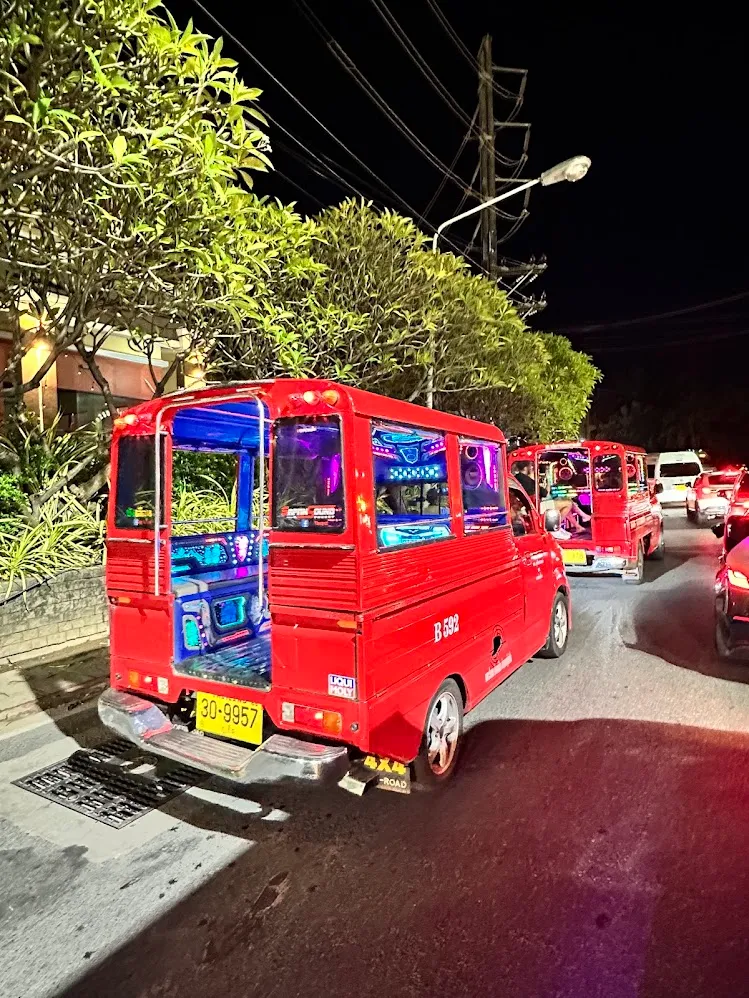 Taxis compartidos rojos y luminosos en una calle nocturna de Tailandia