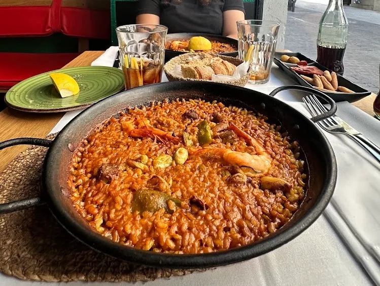 Una paellera con langostinos y arroz en una mesa de restaurante al aire libre