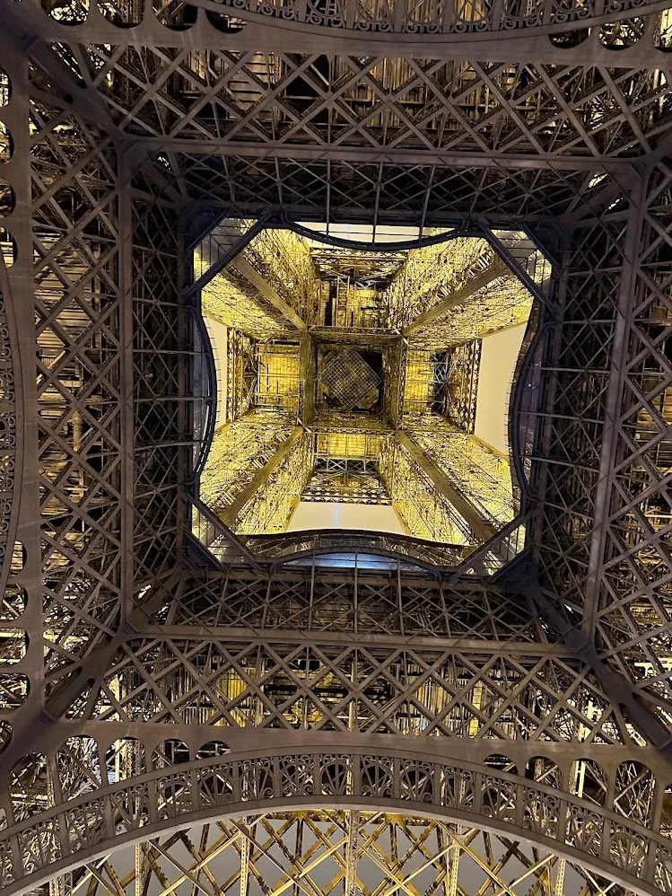 Mirando hacia arriba a través de la estructura de hierro iluminada de la Torre Eiffel de noche