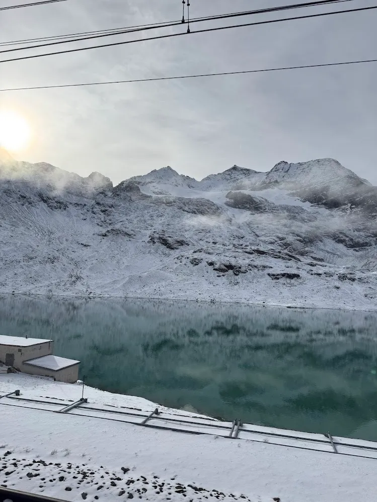 Un lago alpino turquesa rodeado de cumbres nevadas cerca de Poschiavo