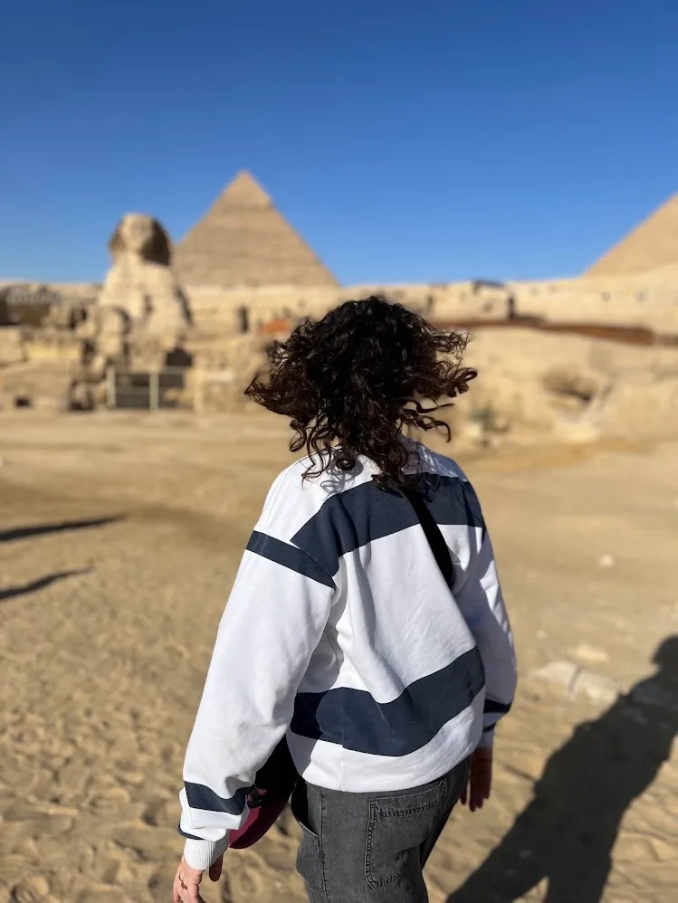 Una viajera caminando hacia la Esfinge y las pirámides de Guiza