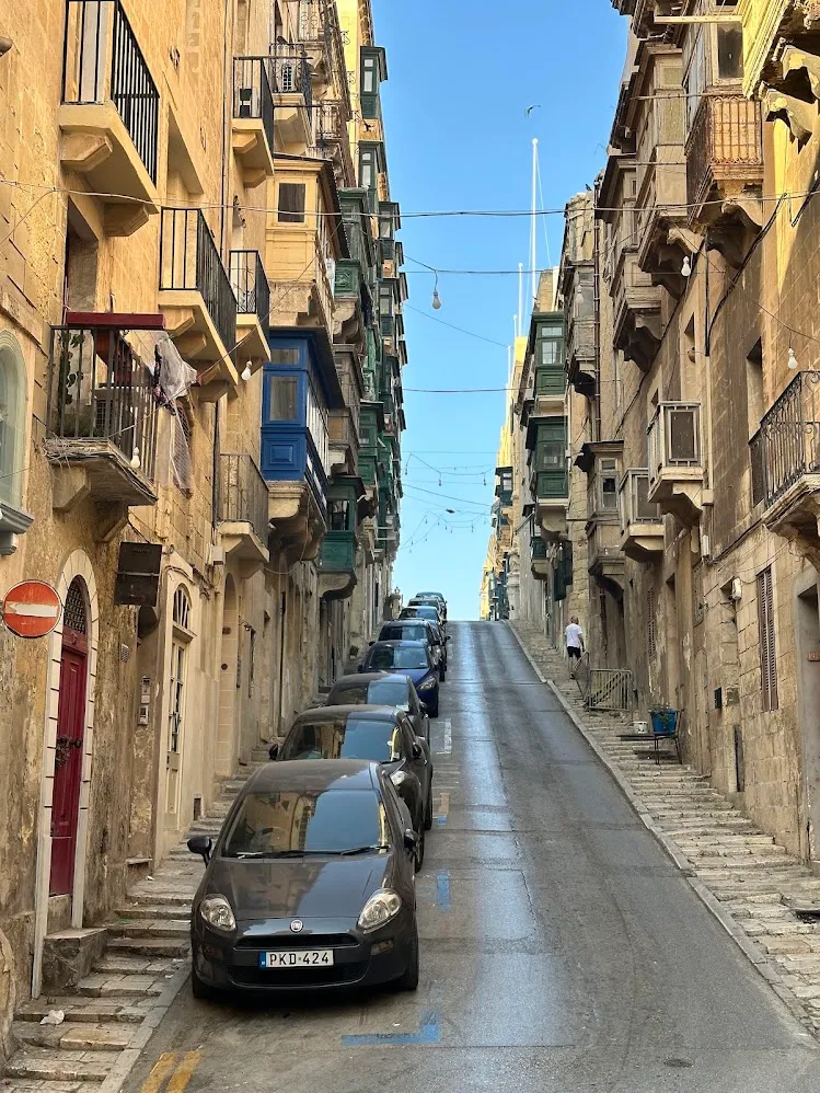 Una calle empinada de La Valeta con balcones tradicionales cerrados